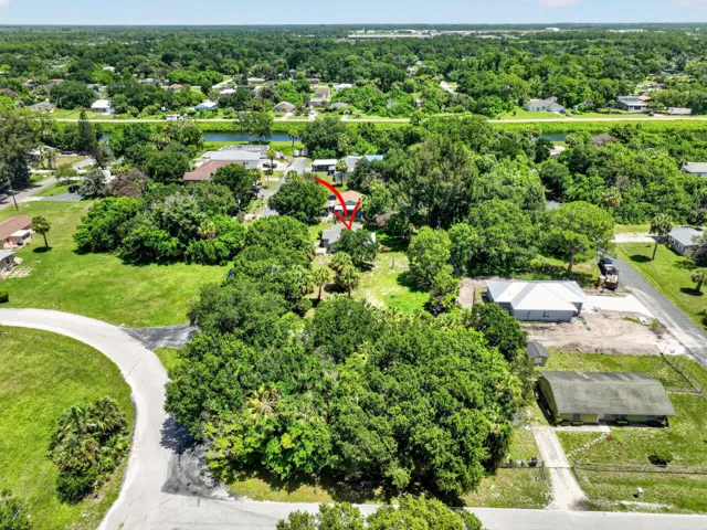 Property situated among mature trees, featuring a surrounding verdant landscape and nearby waterways