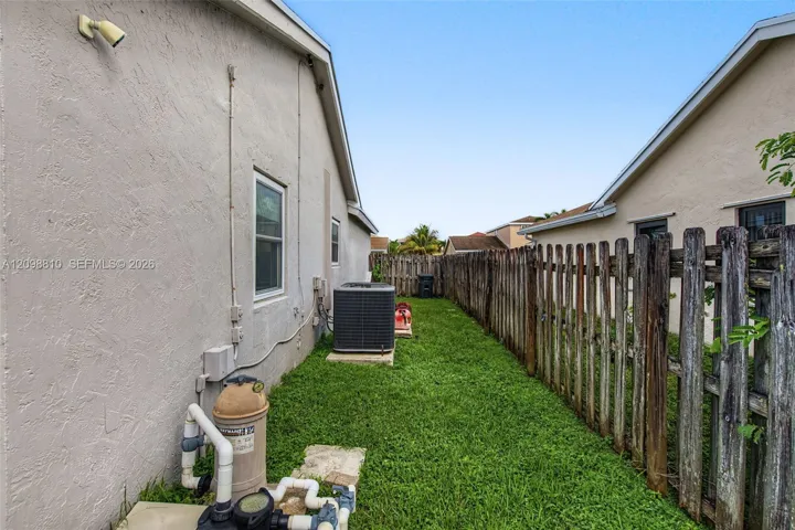 Stucco exterior featuring a side yard, wood-style privacy fencing, and central air conditioning unit