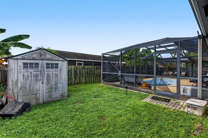 Backyard featuring a screened-in pool enclosure, a detached storage shed, and perimeter wood fencing
