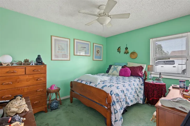 Bedroom featuring carpeting, a ceiling fan with integrated light fixture, and a single-pane window