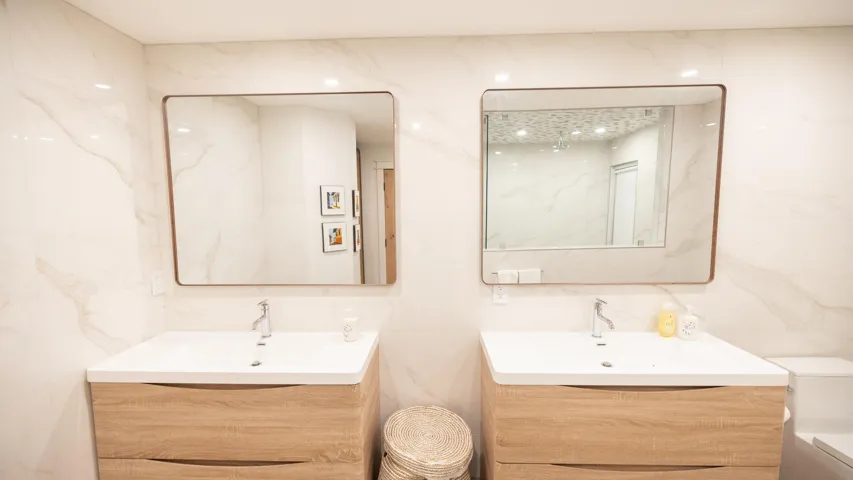 Dual vanity with wood-finish cabinetry, integrated white sinks, and contemporary framed mirrors
