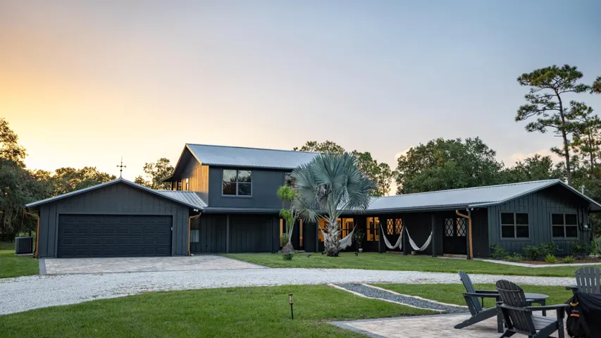 Contemporary dark-toned exterior with a metal roof, an attached two-car garage, and a gravel driveway
