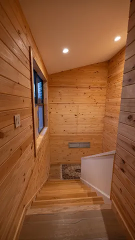 Wood-paneled staircase featuring recessed lighting and a window