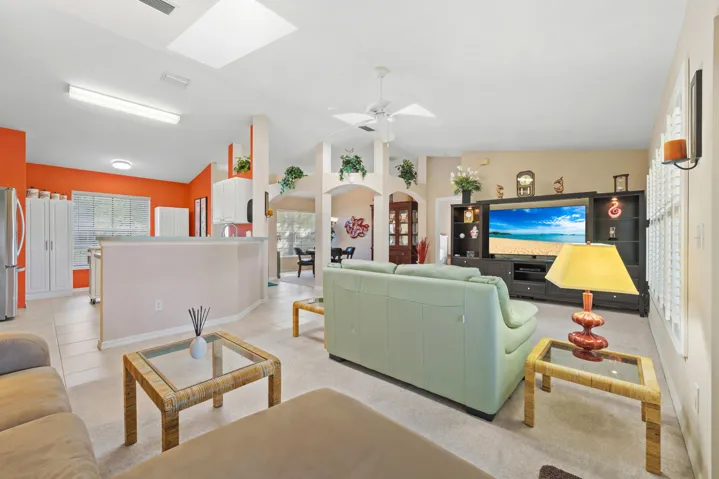 Open-concept main living area featuring vaulted ceilings, built-in shelving, architectural archways, ceramic tile flooring, and a skylight