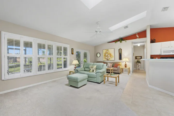 Vaulted ceilings with integrated skylights, plantation shutters, ceiling fan, and ceramic tile flooring