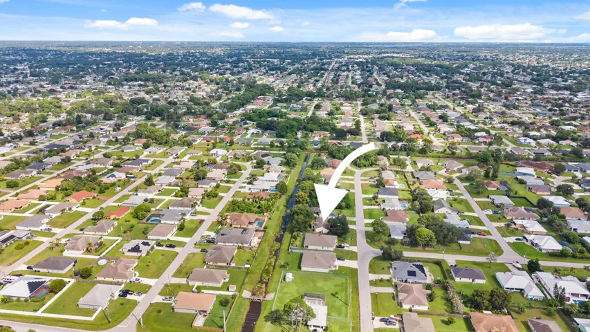 Aerial perspective featuring a detached residential property situated on a corner lot with mature tree canopy and proximity to a canal