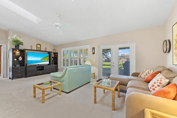 Vaulted ceiling with integrated ceiling fan, built-in cabinetry, dual-pane windows with plantation shutters, and glass-paneled french doors