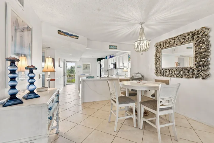 Tile flooring, ornate chandelier, decorative wall mirror, white painted cabinetry, and an open concept layout