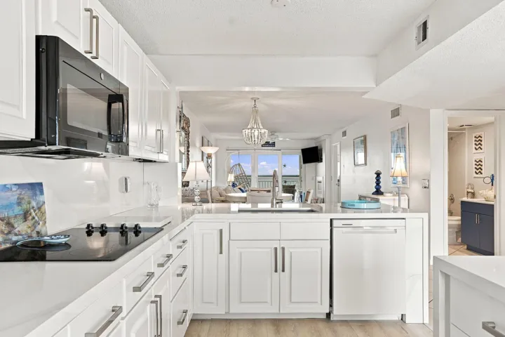 White cabinetry with bar pull hardware, integrated cooktop, built-in microwave, and wood-finish flooring