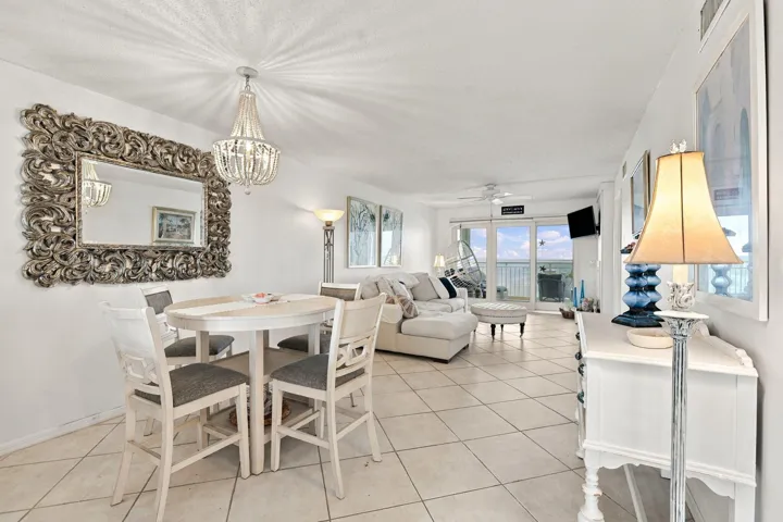 Open-concept living area with tiled flooring, a decorative chandelier, and a mirrored wall accent