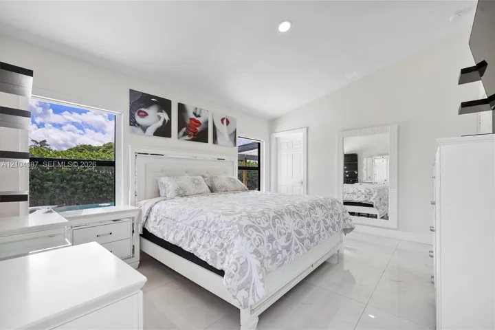 White tile flooring, vaulted ceiling, large windows, recessed lighting, and a white paneled door