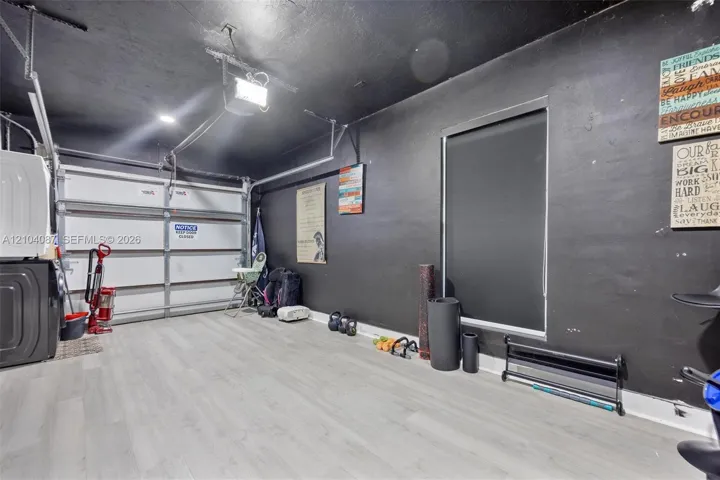 Light wood-finish flooring, overhead lighting, and a window with a blackout shade