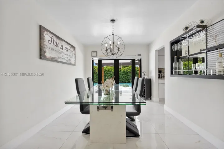 Recessed lighting, large format tile flooring, black multi-pane exterior doors, and a built-in wall bar with mirrored backing