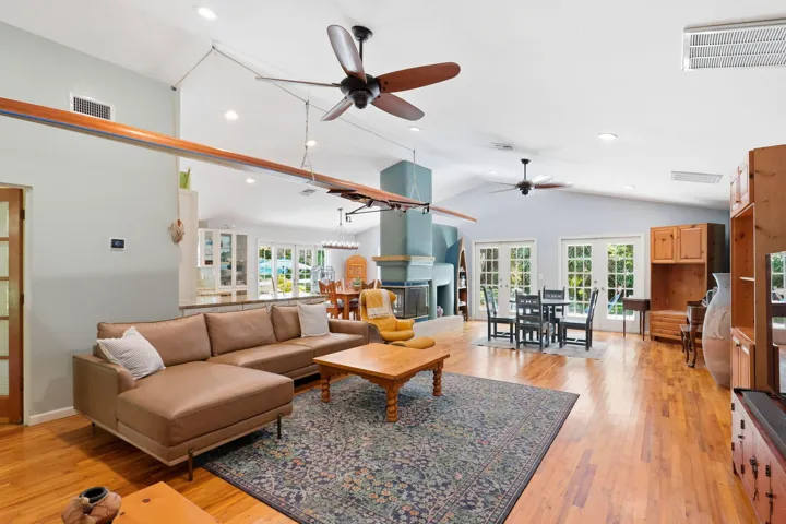 Vaulted ceiling, recessed lighting, oak wood flooring, and a 3 sided wood burning fireplace