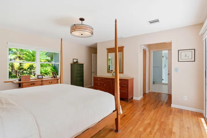 Hardwood flooring, overhead semi-flush mount lighting, recessed window, and wall-mounted mirror