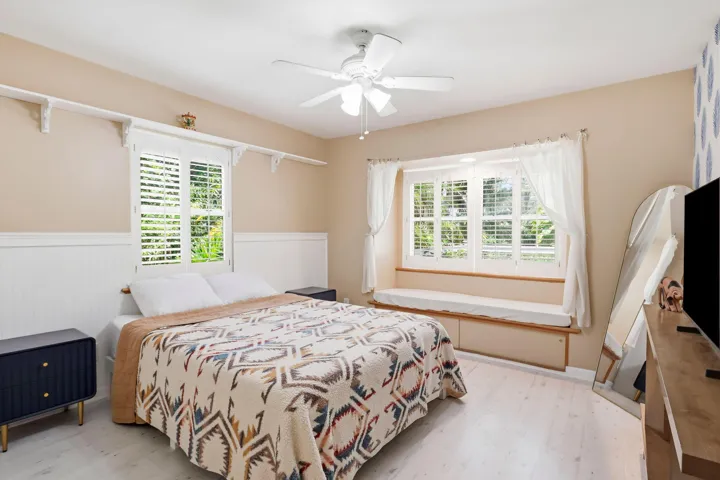 White wood-finish flooring, built-in window bay window seat, plantation shutters, and beadboard wainscoting