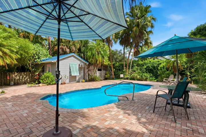 In-ground swimming pool with handrails, surrounded by a paver patio