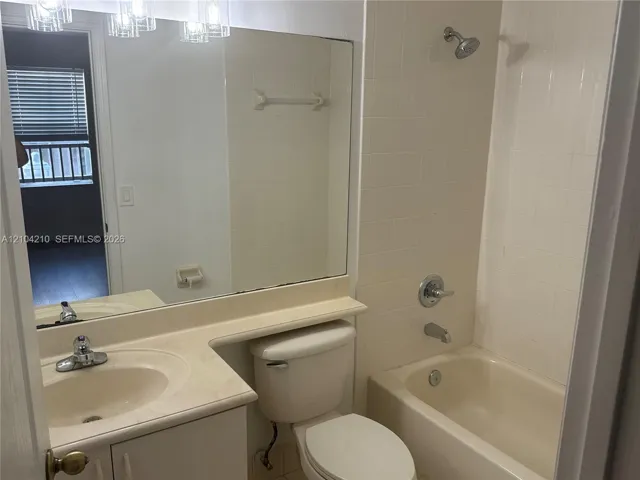 Bathroom featuring a single vanity, integrated sink, large mirror, and a shower-tub combination with tile surround