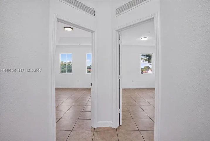 Neutral tile flooring, flush-mount ceiling lighting, multi-pane windows, and tray ceiling detailing