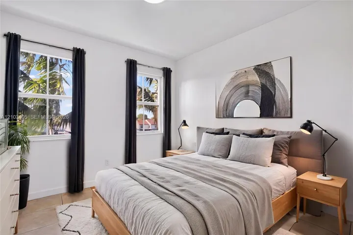 Neutral-toned interior space featuring light-colored tile flooring, dual-pane windows with white muntins, and crisp white wall finishes