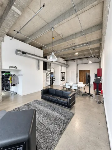 Industrial-style interior featuring exposed concrete ceilings, polished concrete flooring, metal spiral staircase, pendant lighting, and exposed ductwork