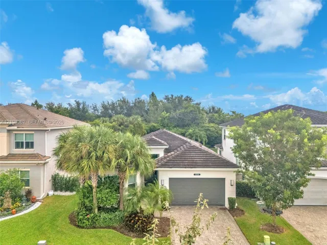 Single-story residence featuring a concrete tile roof, paver driveway, and an attached two-car garage