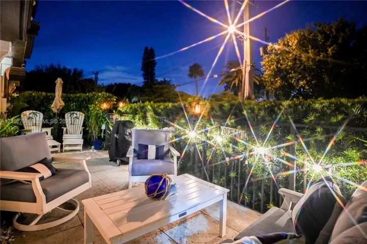 Outdoor paved patio featuring perimeter hedge landscaping and metal railing