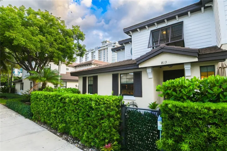Multi-story exterior featuring lap siding, decorative shutters, a covered entryway, and landscaped hedging