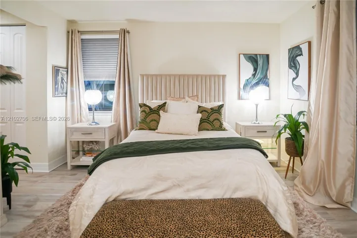 Bedroom featuring neutral walls, wood-finish flooring, and a double-door closet with paneled detailing