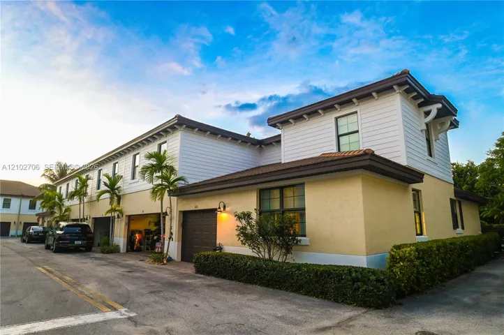 Two-story exterior featuring a stucco and horizontal siding facade, multiple garage bays, decorative roof brackets, and a tiled roof
