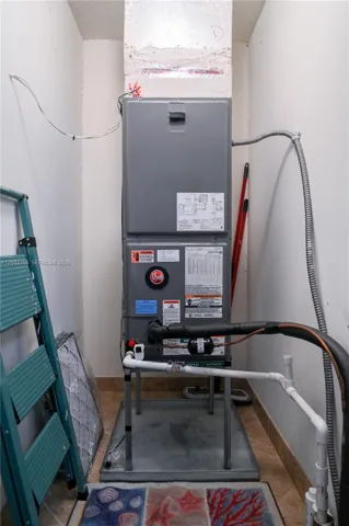 Upright HVAC unit featuring a metal enclosure, protective drain pan, and dedicated plumbing components