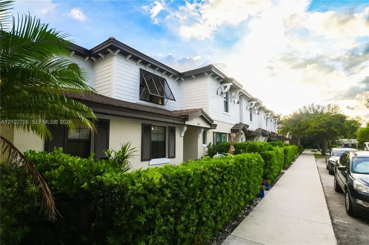 Two-story exterior featuring white horizontal siding, dark window shutters, ornamental roof brackets, and gooseneck wall-mounted light fixtures