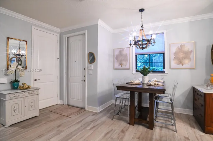 Dining area featuring wood-finish flooring, crown molding, a multi-light metal chandelier, and a multi-pane window