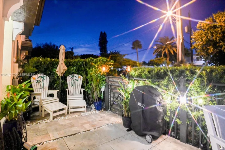 Patio featuring large-format stone pavers, integrated metal privacy fencing, and lush perimeter shrubbery