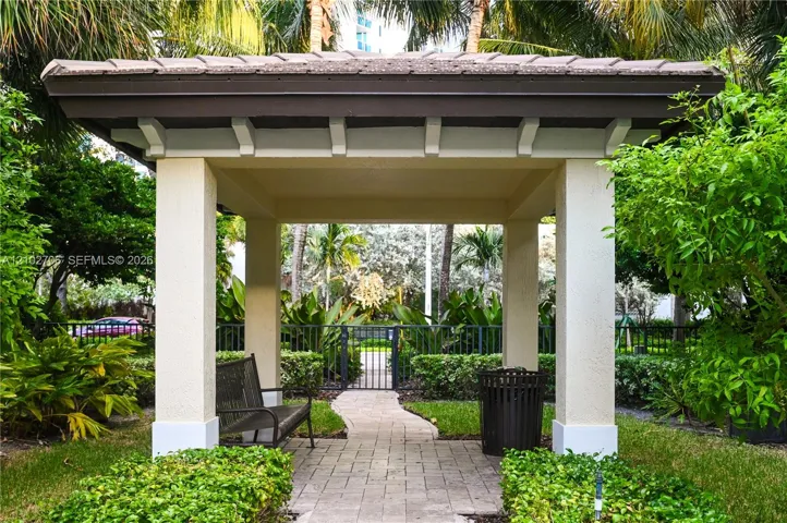 Covered pavilion featuring a tiled roof, stucco-finished columns, and a stone-paver walkway