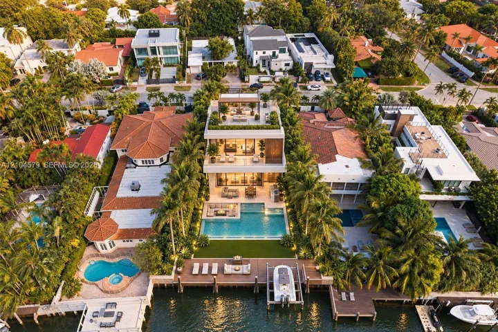 Modern waterfront residence featuring multiple balconies, a rooftop deck, an expansive private pool, and private boat dockage