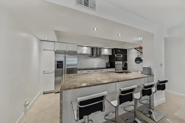 Kitchen with oversized island, granite countertop with waterfall side