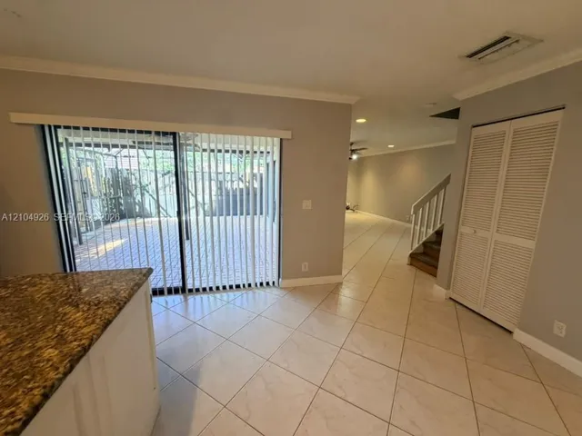 Ceramic tile flooring, stone-surfaced countertop, sliding glass doors, louvered bi-fold closet doors, and interior staircase with wood-finished steps