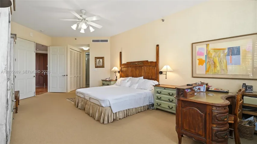 Spacious room featuring neutral carpeting, a central ceiling fan with integrated lighting, dual hinged doors, and bi-fold closet doors