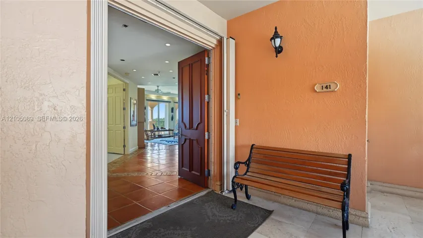Entryway featuring a solid wood door with decorative paneling, recessed lighting, and tile flooring