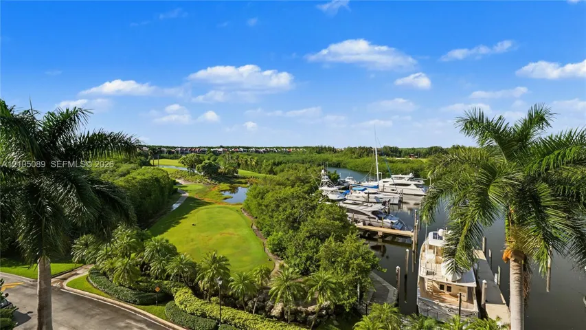Waterfront setting featuring a private boat slip, manicured golf course grounds, native mangroves, and mature palm trees