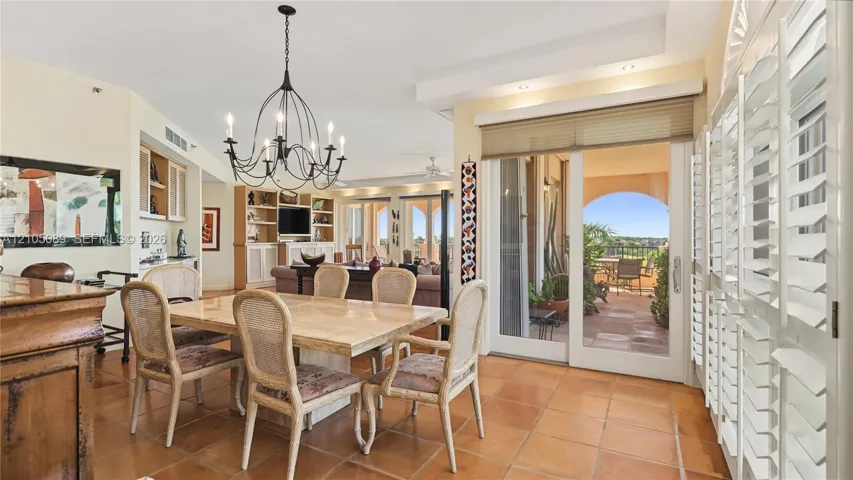 Dining area featuring tile flooring, a multi-arm metal chandelier, built-in cabinetry, and sliding glass doors with plantation shutters
