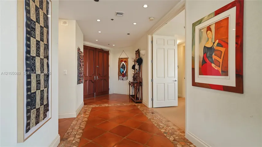 Foyer featuring double-panel wood entry doors, recessed ceiling lighting, and tile flooring with decorative stone border accents