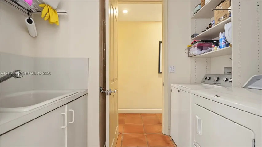 Utility room featuring a built-in sink with cabinetry, ceramic tile flooring, and integrated shelving