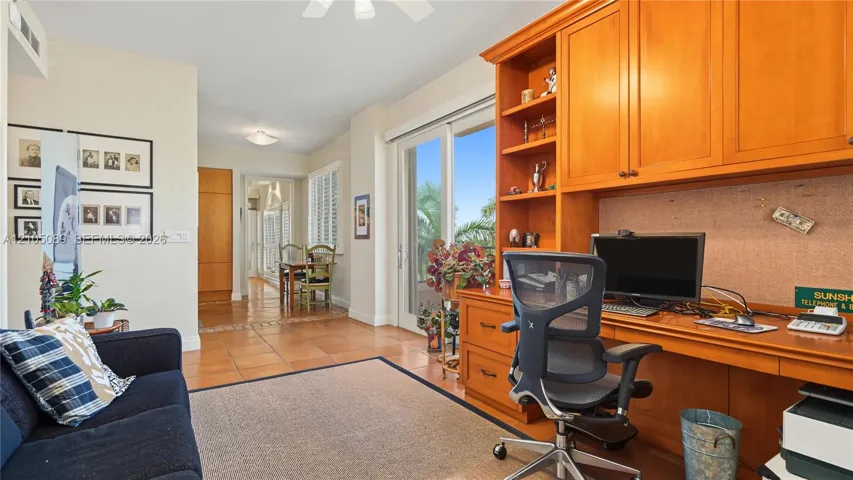Custom built-in cabinetry featuring extensive shelving and desk workspace, ceramic tile flooring, and glass sliding doors