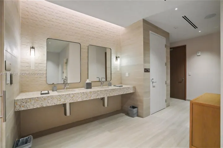 Floating double vanity with a speckled countertop, undermount sinks, and wall-mounted faucets