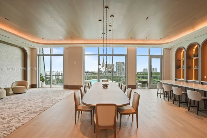 Expansive room featuring wood-finish flooring, a full wall of floor-to-ceiling windows, built-in shelving with arched accents, and recessed ceiling lighting