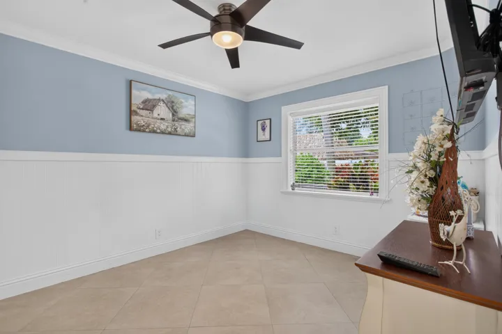 Room featuring crown molding, a ceiling fan, tile flooring, and wainscoting
