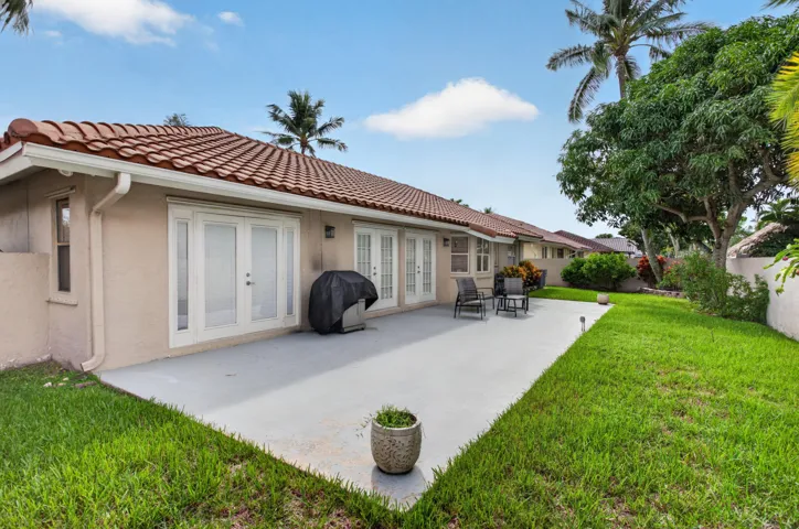 Great entretaining private patio, multiple sets of French doors, stucco exterior, red tile roof, and a large grassy yard
