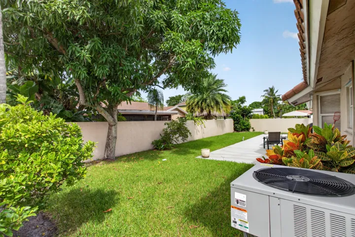 nicely done green lawn, mature trees, concrete patio, vibrant landscaping, and a privacy wall